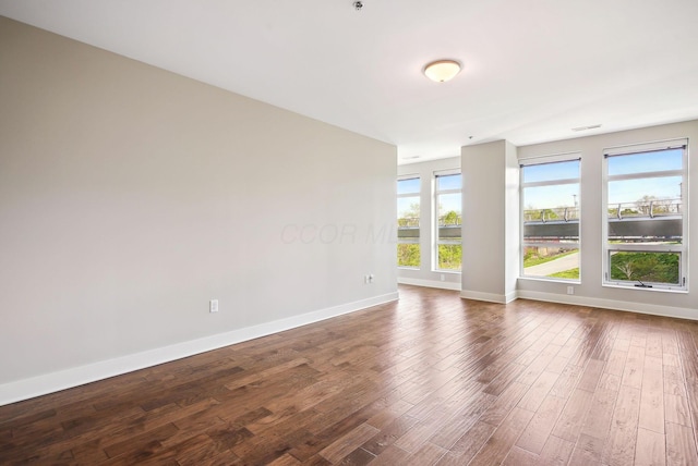 empty room with dark wood-type flooring and baseboards