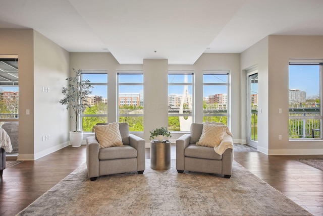 sunroom / solarium featuring wood-type flooring, baseboards, and healthy amount of natural light
