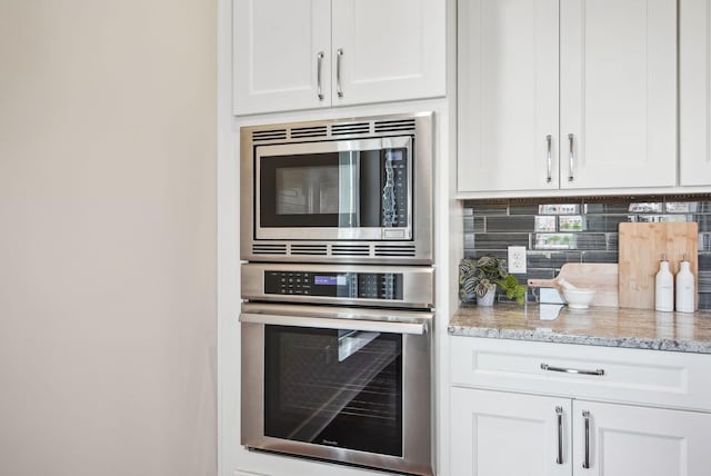kitchen featuring appliances with stainless steel finishes, tasteful backsplash, white cabinetry, and light stone counters