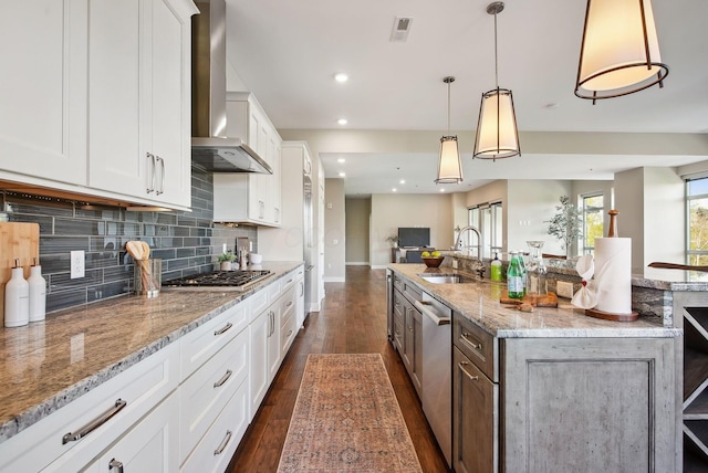 kitchen featuring a sink, wall chimney range hood, open floor plan, dark wood finished floors, and backsplash