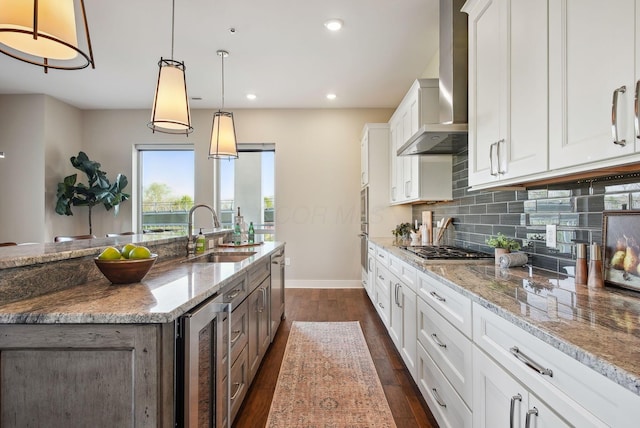 kitchen with a sink, wine cooler, wall chimney exhaust hood, baseboards, and dark wood-type flooring