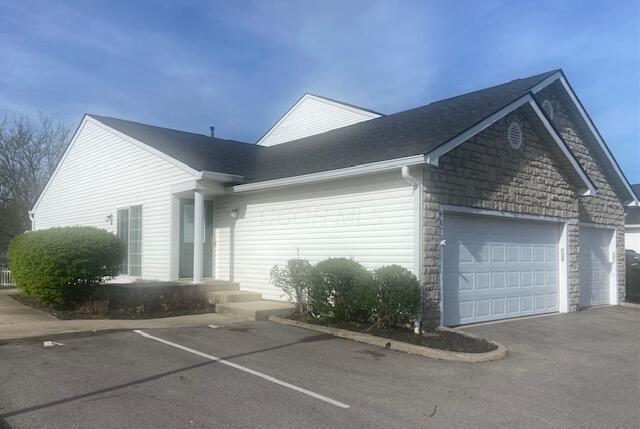 view of property exterior featuring a garage, aphalt driveway, and stone siding