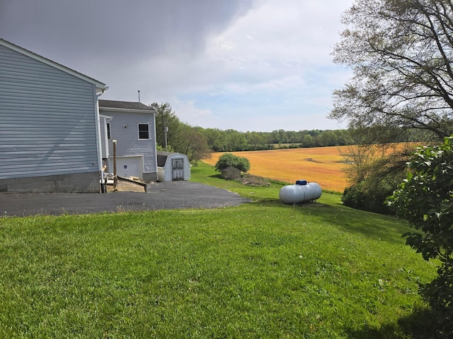 view of yard with an outbuilding, a shed, and aphalt driveway