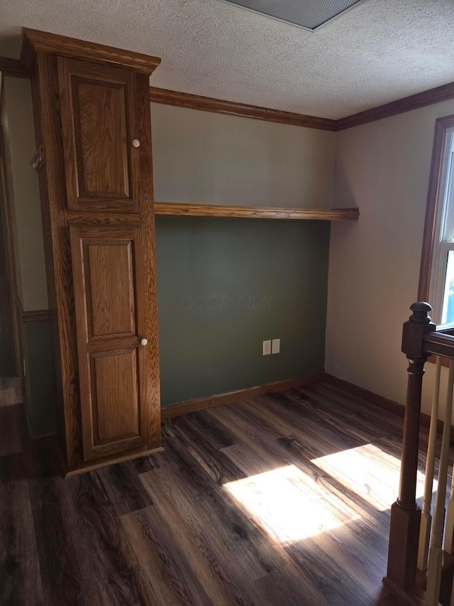 spare room with crown molding, dark wood-style flooring, and a textured ceiling