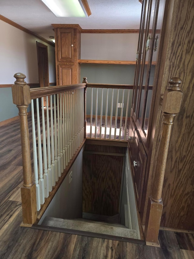 staircase featuring crown molding, baseboards, and wood finished floors