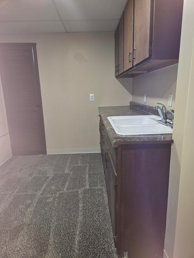 laundry area with a sink, baseboards, and dark carpet
