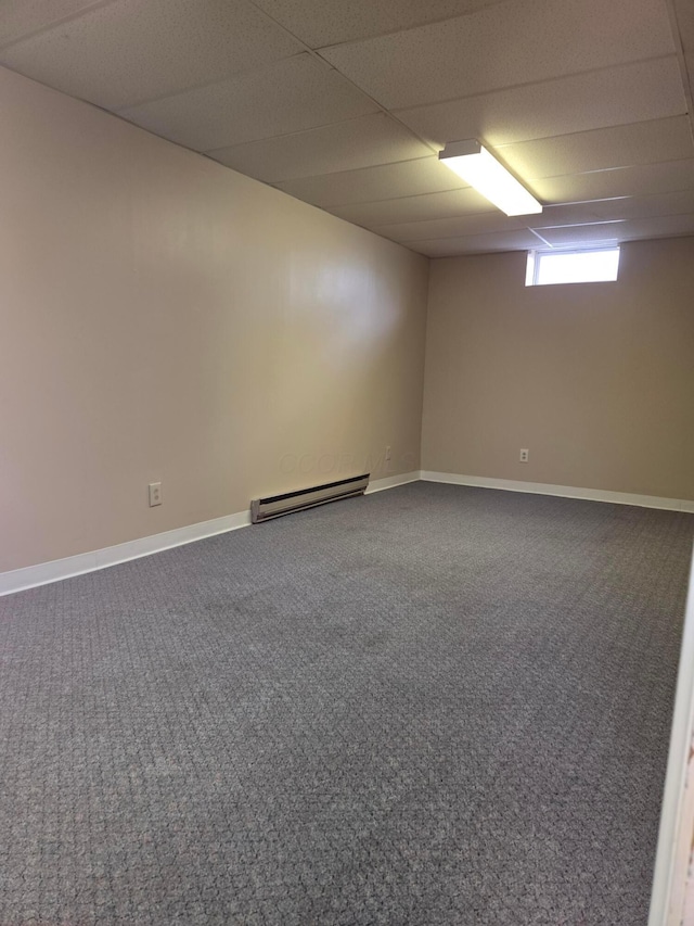 empty room with carpet floors, baseboards, a paneled ceiling, and a baseboard radiator
