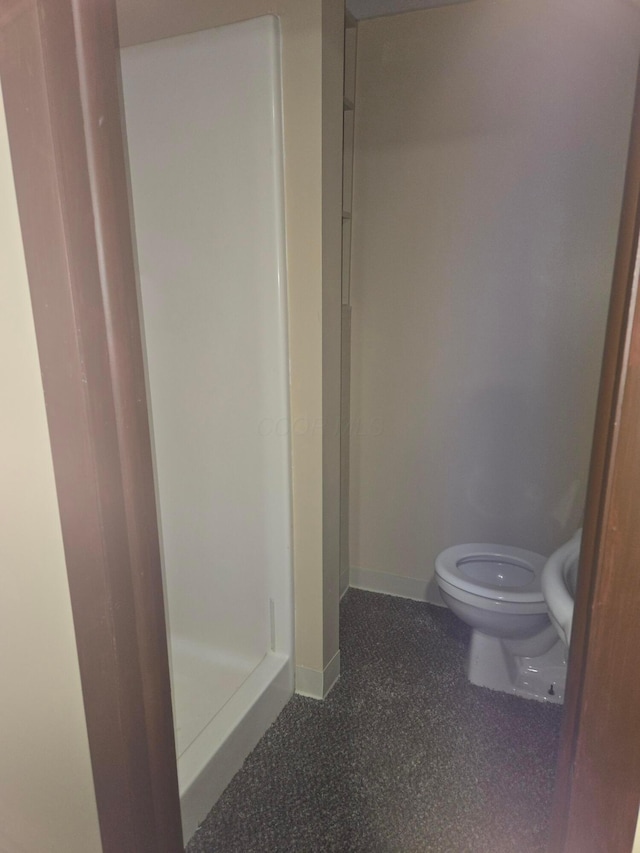 full bathroom with baseboards, a shower stall, and toilet