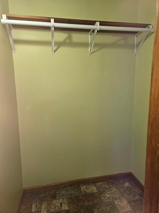 walk in closet featuring stone finish floor