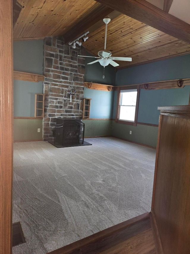 unfurnished living room with wooden ceiling, ceiling fan, lofted ceiling with beams, and a wainscoted wall