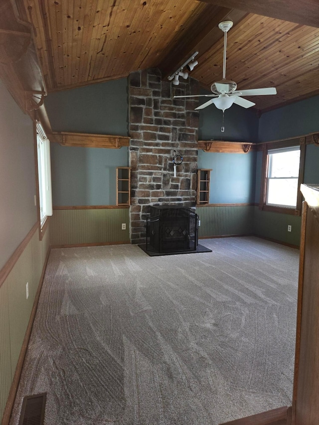 unfurnished living room with wood ceiling, a ceiling fan, a wainscoted wall, lofted ceiling with beams, and carpet