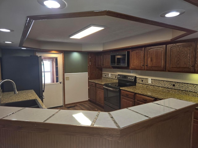 kitchen with black electric range oven, dark wood-type flooring, stainless steel microwave, a sink, and backsplash