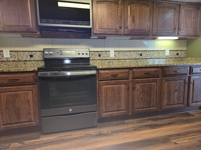 kitchen featuring dark wood-type flooring, stone counters, tasteful backsplash, and stainless steel appliances