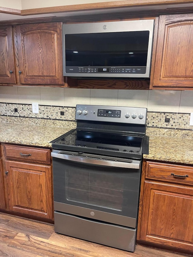 10519 Darby Creek Rd, Orient, OH 43146 - kitchen with stainless steel appliances, tasteful backsplash, light wood-style floors, and light stone counters