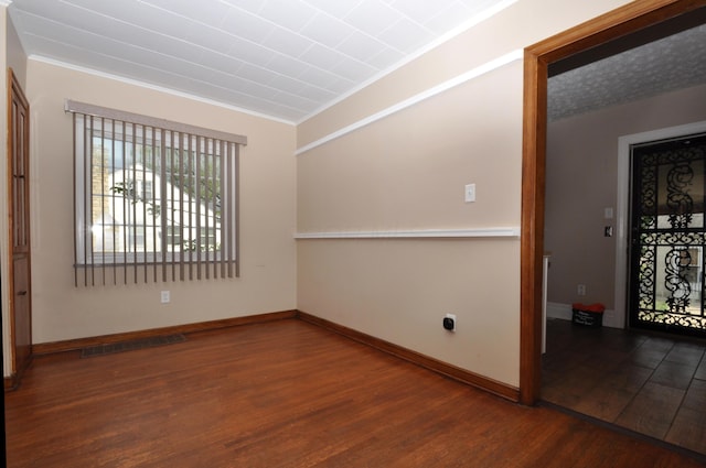 spare room with baseboards, visible vents, ornamental molding, and wood finished floors