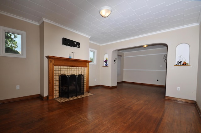 unfurnished living room featuring arched walkways, wood finished floors, a healthy amount of sunlight, and ornamental molding