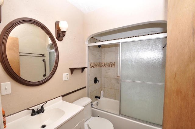 full bath featuring vanity, combined bath / shower with glass door, and toilet