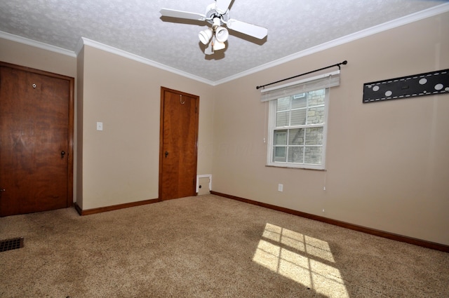 carpeted spare room with crown molding, a ceiling fan, baseboards, and visible vents