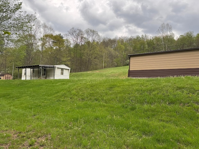 view of yard featuring an outdoor structure, an outbuilding, and a wooded view