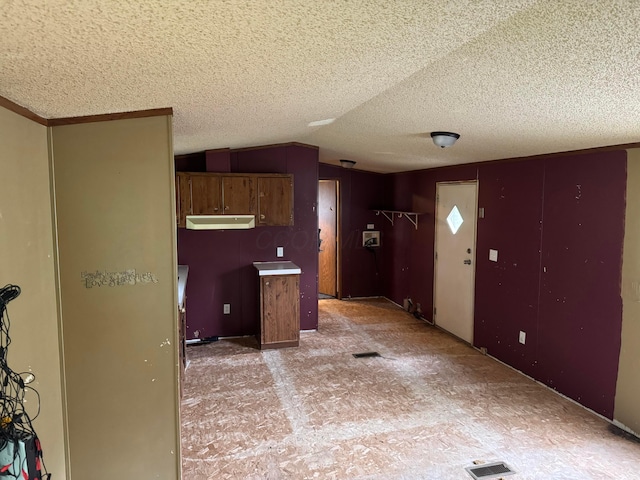 kitchen featuring visible vents, a textured ceiling, lofted ceiling, and brown cabinets