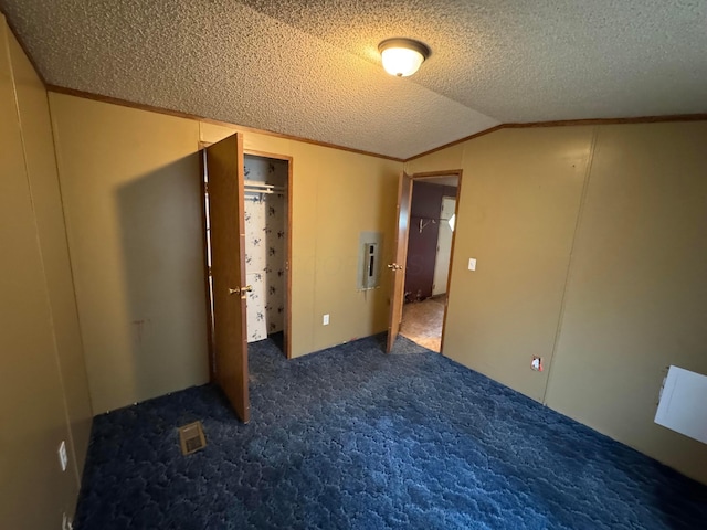 unfurnished bedroom with carpet floors, vaulted ceiling, and a textured ceiling