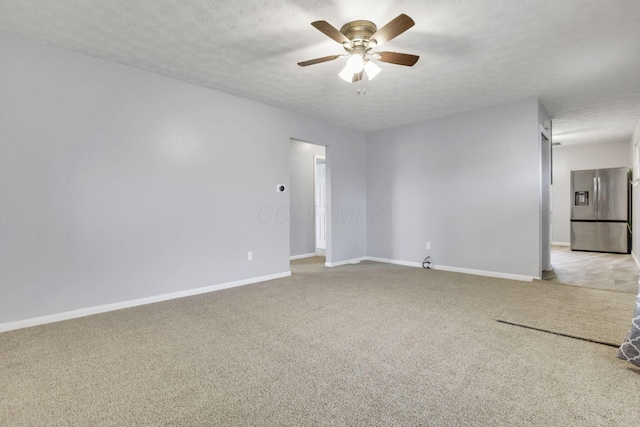 empty room featuring light colored carpet, a textured ceiling, baseboards, and ceiling fan