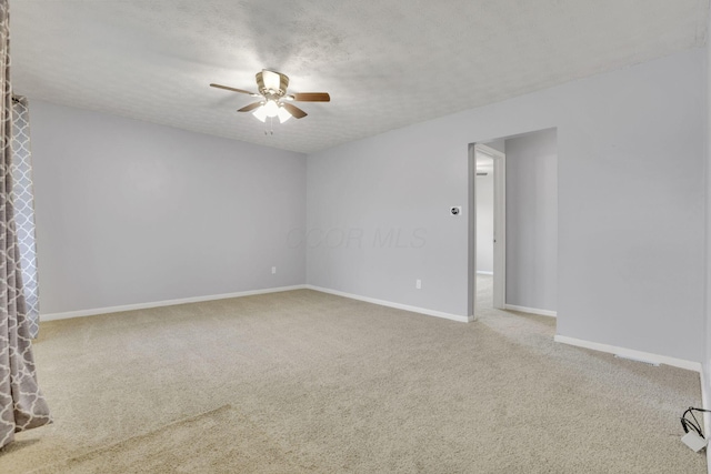 empty room featuring baseboards, ceiling fan, carpet flooring, and a textured ceiling