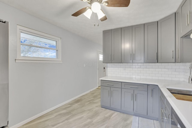 kitchen with decorative backsplash, gray cabinets, ceiling fan, and light countertops