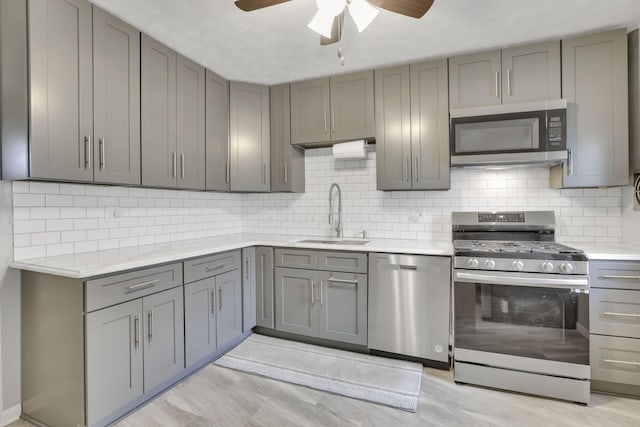 kitchen with ceiling fan, light countertops, gray cabinets, a sink, and stainless steel appliances