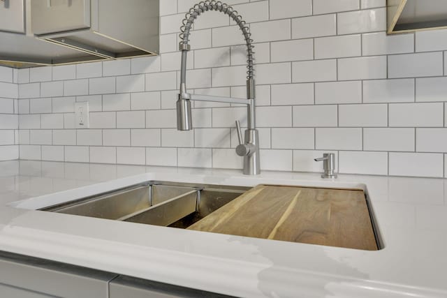 kitchen with a sink, backsplash, and light countertops