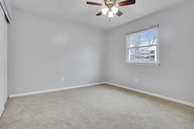 empty room with carpet flooring, a ceiling fan, and baseboards