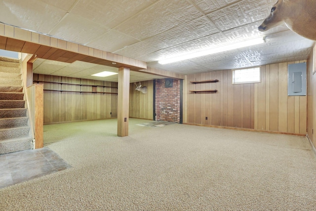 basement featuring stairway, electric panel, carpet flooring, and wood walls