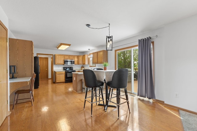 dining space featuring baseboards and light wood-style flooring
