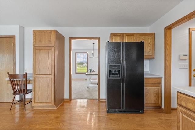 kitchen featuring black fridge, light wood-style flooring, light countertops, and baseboards