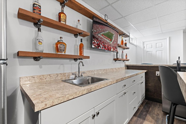 bar with a paneled ceiling, wet bar, dark wood-style flooring, and a sink