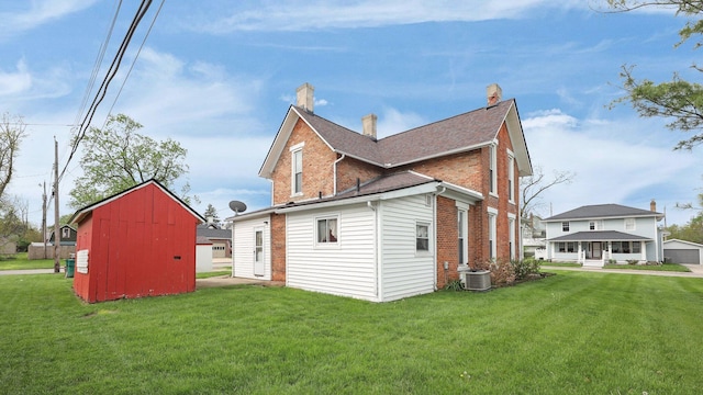 74 S Chester St, West Jefferson, OH 43162 - rear view of house featuring a lawn, an outbuilding, cooling unit, and brick siding