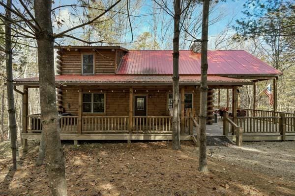 log cabin featuring a porch, log siding, and metal roof