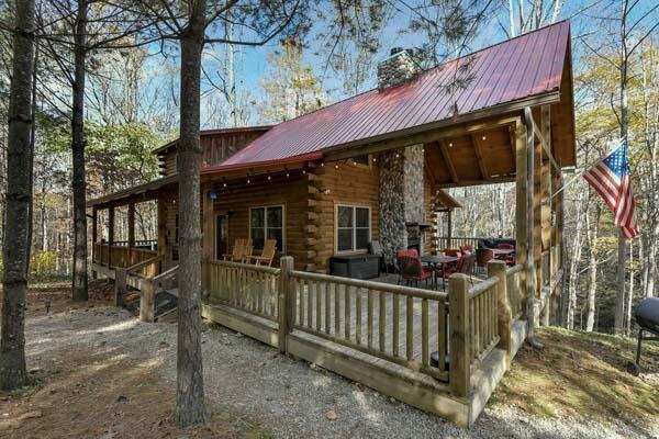 rear view of house with log siding, a chimney, and metal roof