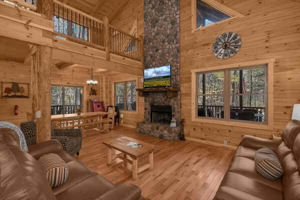 living area with a healthy amount of sunlight, high vaulted ceiling, wood walls, and wood finished floors