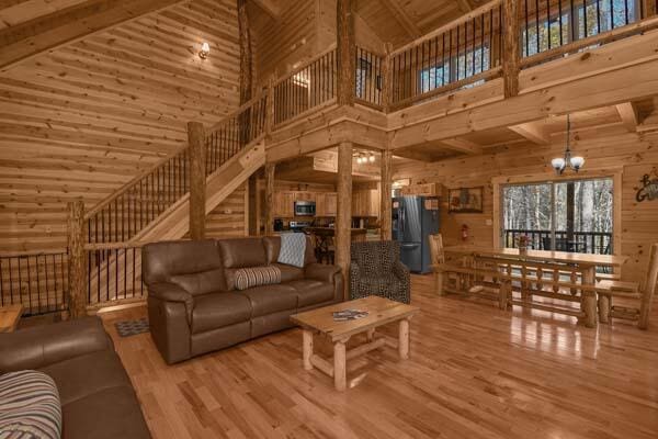 living room with beam ceiling, wood finished floors, wooden walls, high vaulted ceiling, and a notable chandelier