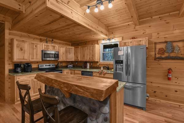 kitchen featuring light brown cabinets, beamed ceiling, wood ceiling, light wood finished floors, and appliances with stainless steel finishes