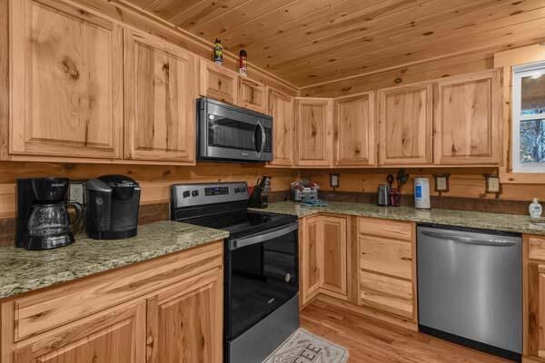 kitchen featuring light brown cabinets, light stone countertops, wood ceiling, light wood finished floors, and stainless steel appliances