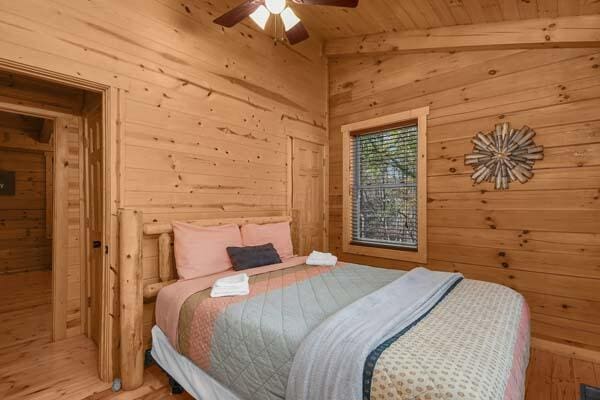 bedroom with wood ceiling, ceiling fan, wooden walls, and beamed ceiling