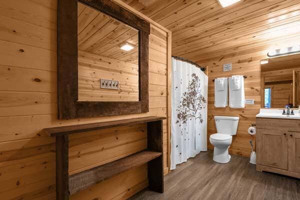 full bath with vanity, toilet, wood walls, wooden ceiling, and wood finished floors