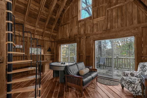 sitting room featuring wooden walls, high vaulted ceiling, and a wealth of natural light
