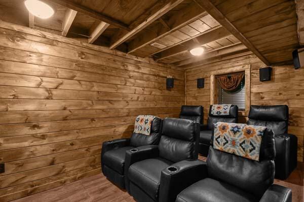 cinema room with beam ceiling, wood walls, wood finished floors, and wooden ceiling