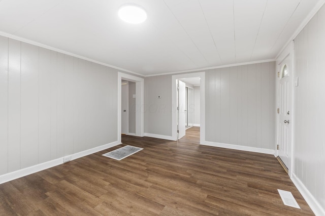 empty room with wood finished floors, ornamental molding, and baseboards