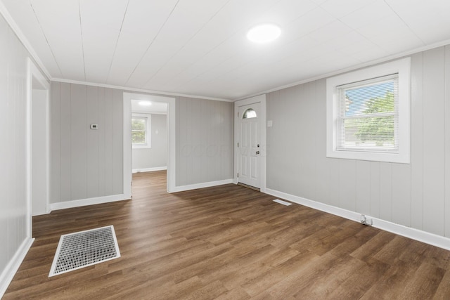 unfurnished living room featuring wood finished floors, ornamental molding, and baseboards