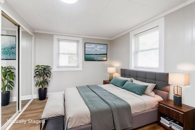 bedroom with wood finished floors, a closet, and crown molding