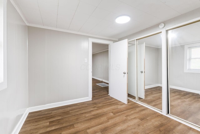 unfurnished bedroom featuring wood finished floors, ornamental molding, and baseboards
